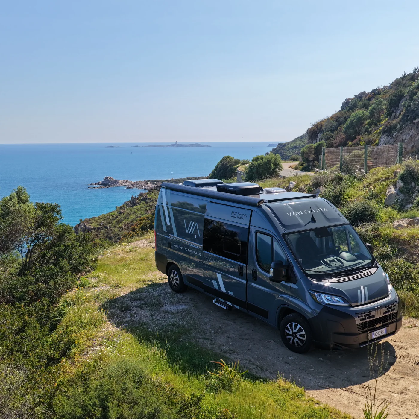 I nostri van sono targati Nomade Nation Camper Vanthura parcheggiato vicino alla scogliera con vista mare in Sardegna.