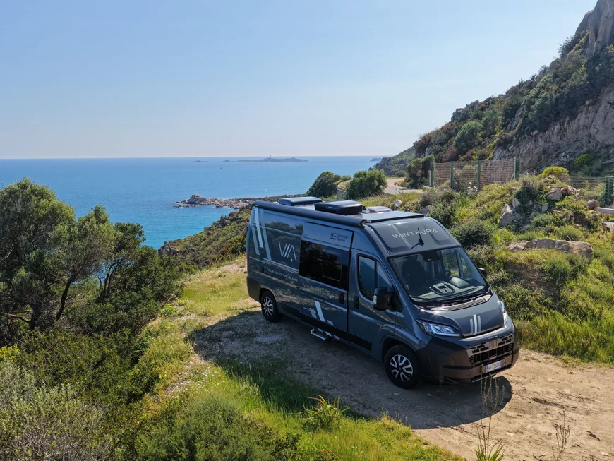 I nostri van sono targati Nomade Nation Camper Vanthura parcheggiato vicino alla scogliera con vista mare in Sardegna.
