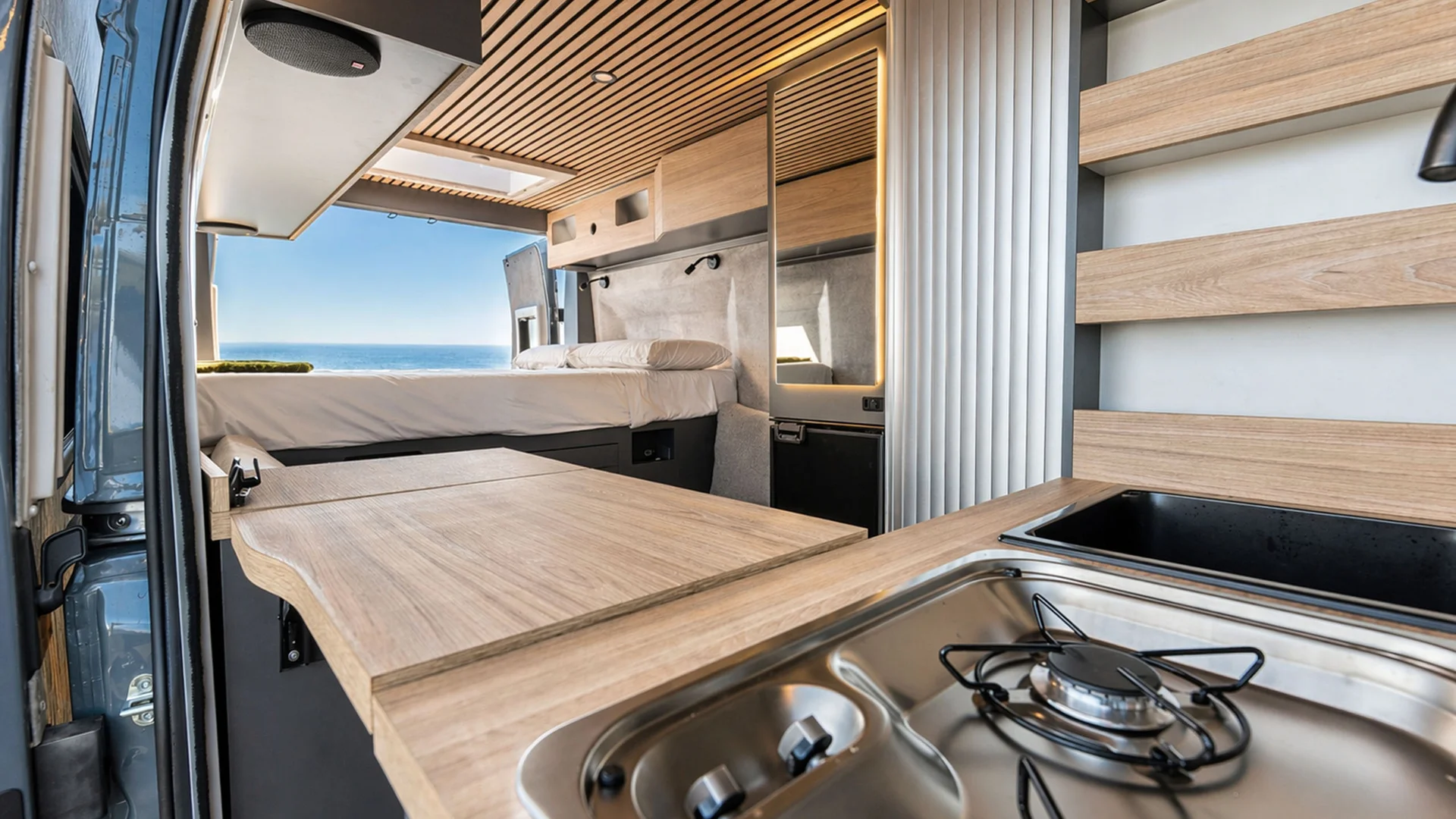 Modernes Camper-Innere mit Küche und Bett mit Meerblick