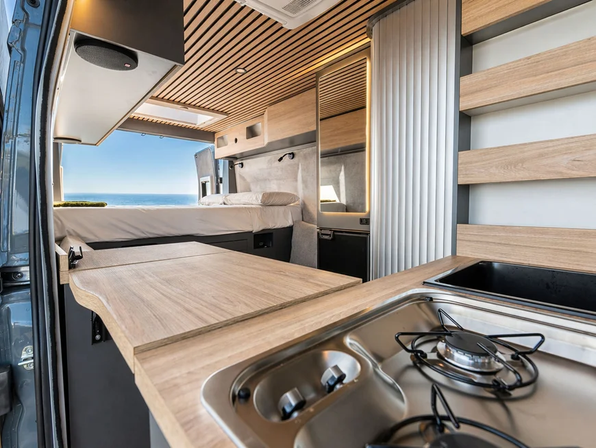 Modernes Camper-Innere mit Küche und Bett mit Meerblick
