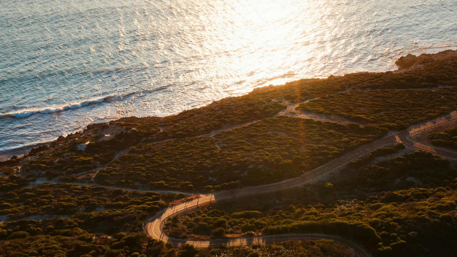 Strada tortuosa lungo la costa al tramonto con vegetazione verde
