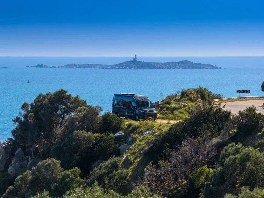 Wohnmobil auf Klippe mit Meerblick und Leuchtturm auf entfernter Insel