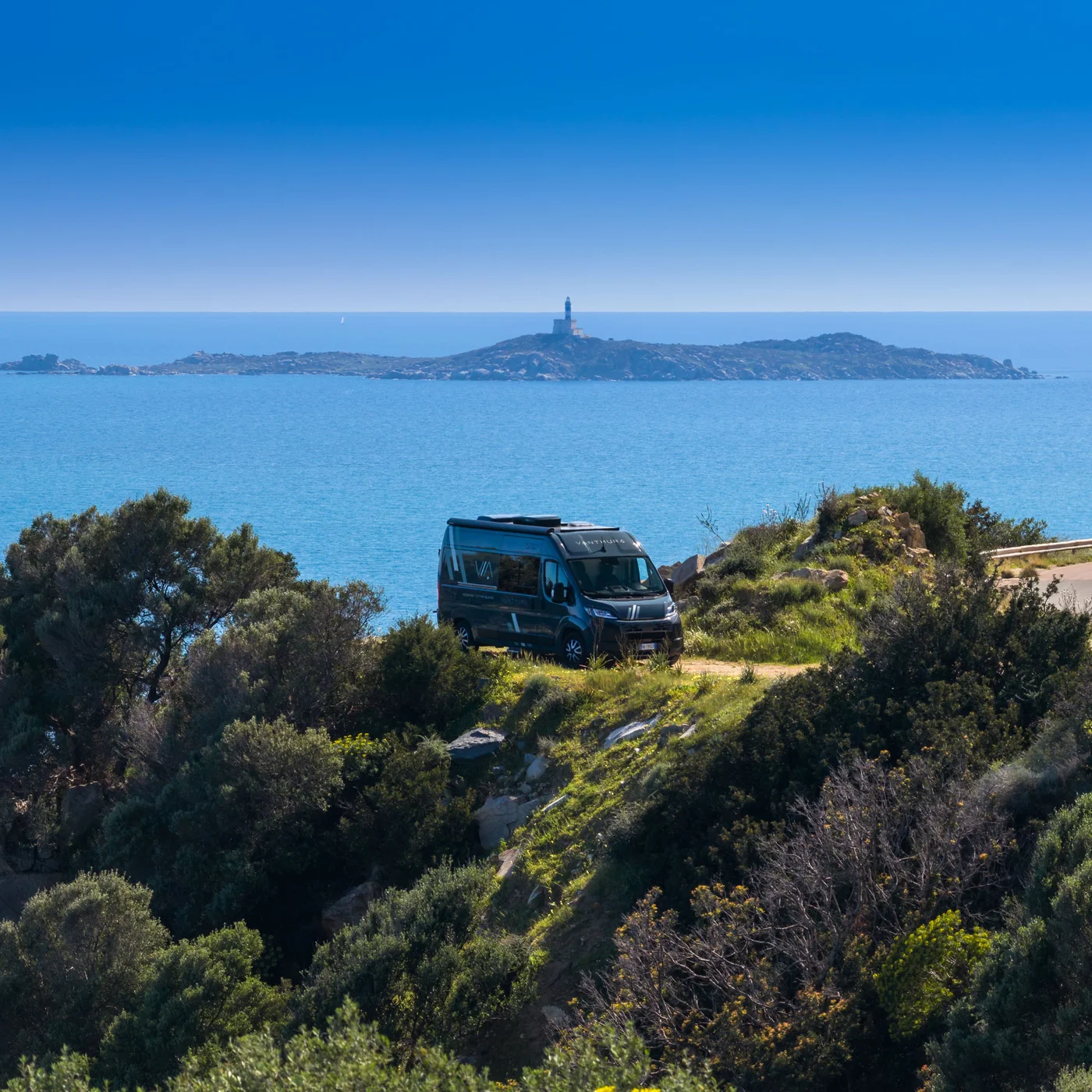 Wohnmobil auf Klippe mit Meerblick und Leuchtturm auf entfernter Insel