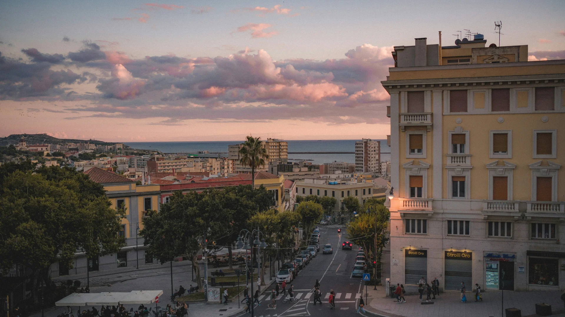 Vista urbana al tramonto con palazzi, strade e nuvole colorate