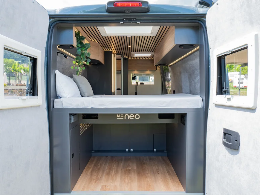 Interno di un camper moderno con letto e spazio di stivaggio sottostante