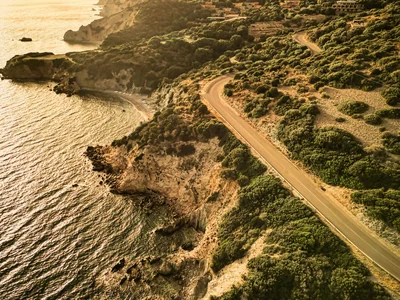 Strada costiera curva al tramonto con colline e mare