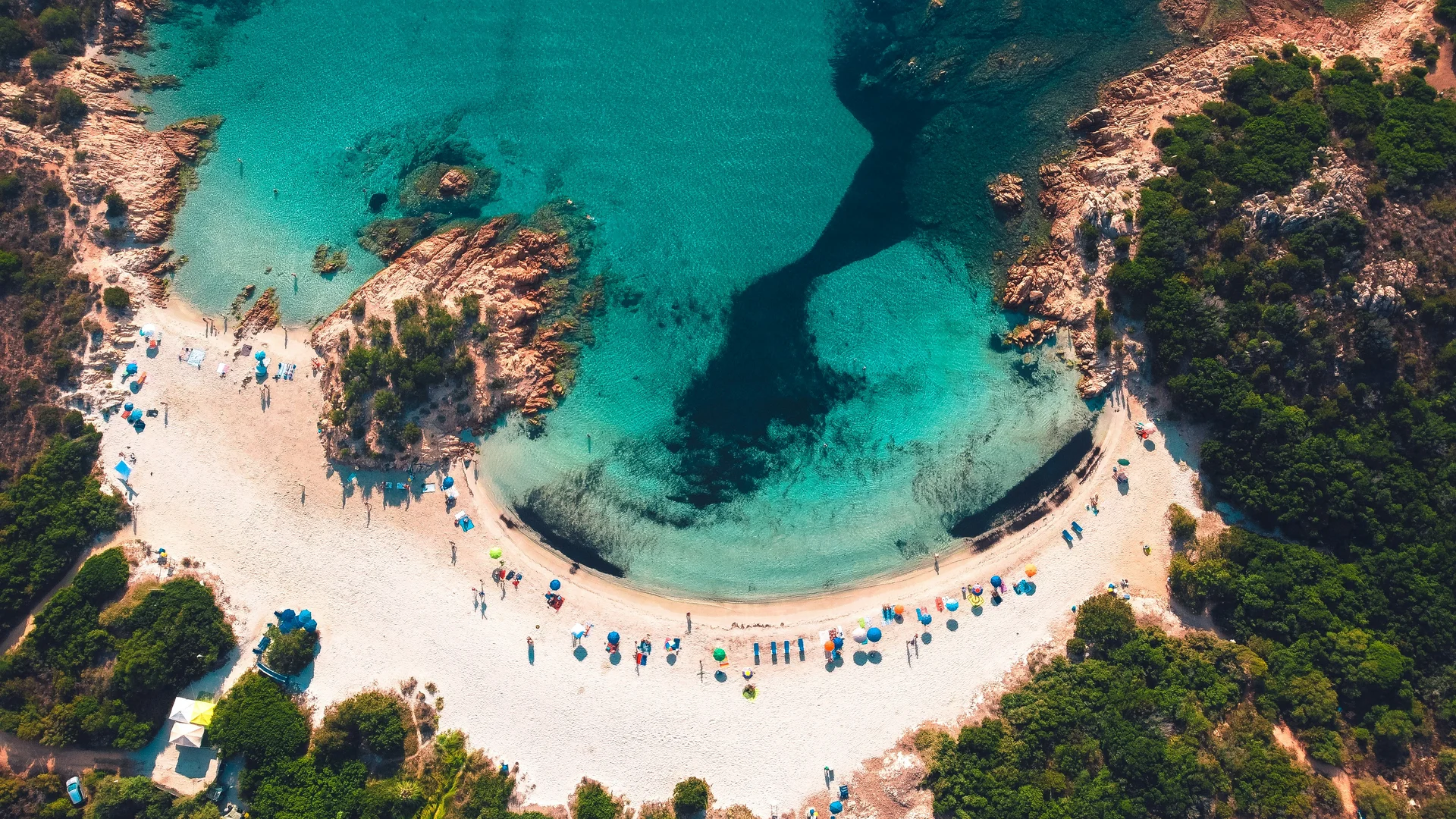 Spiaggia con sabbia bianca e ombrelloni colorati vista dall'alto
