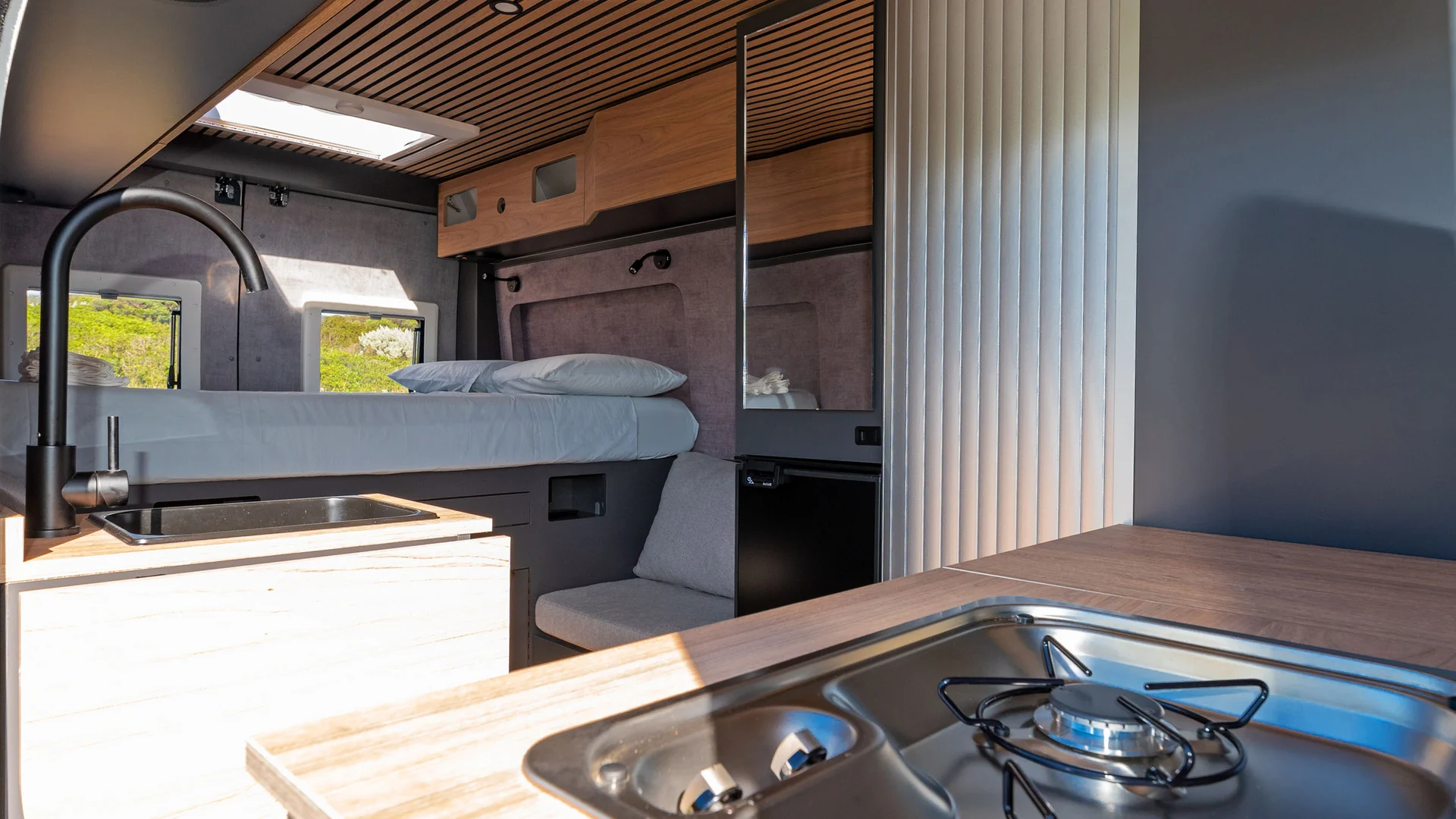 Modernes Wohnmobil-Innere mit Küche, Bett und Holzmöbeln