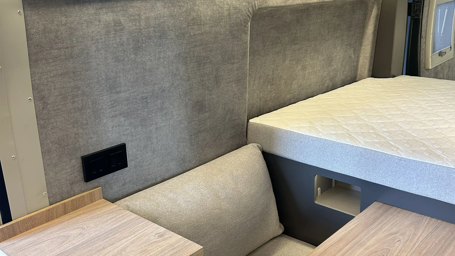 Interno di camper con letto, divano e mobili in legno chiaro