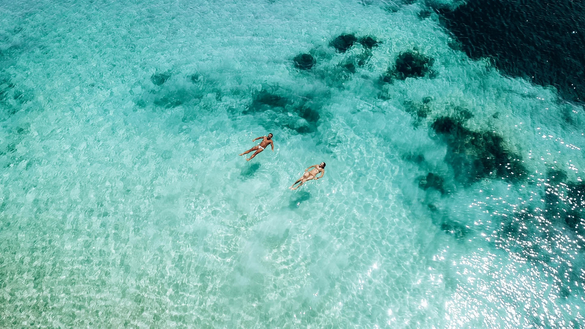 Due persone che nuotano in acqua limpida e turchese vista dall'alto