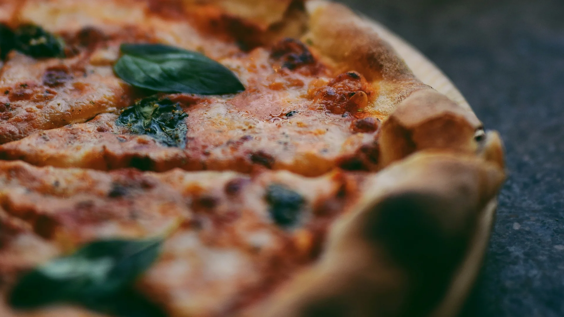 Pizza Margherita con basilico su tavolo scuro