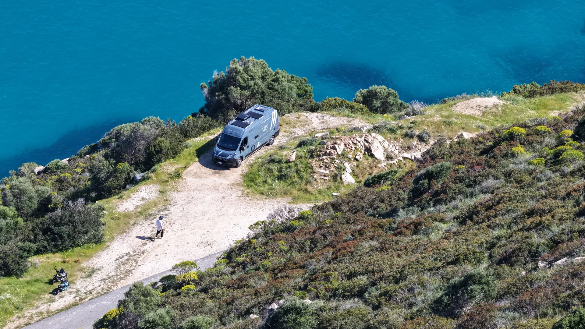 Van auf einer Klippe mit Blick auf türkisfarbenes Wasser geparkt