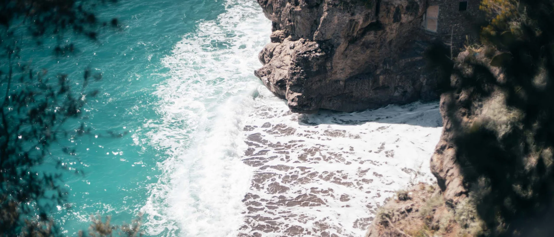 Vista dall'alto sulla costa rocciosa con onde bianche e mare turchese