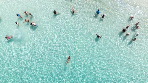 Persone che nuotano e si divertono in acqua chiara e poco profonda