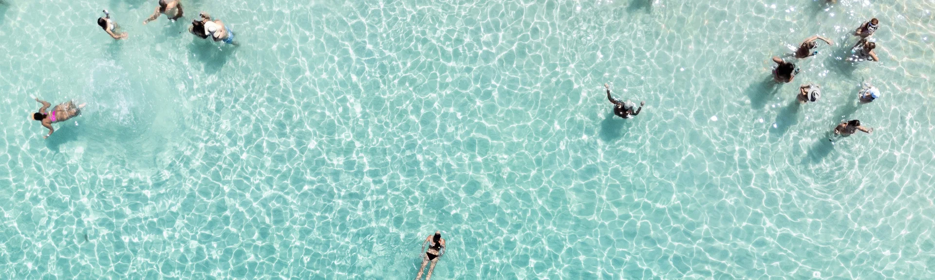 Persone che nuotano e si divertono in acqua chiara e poco profonda
