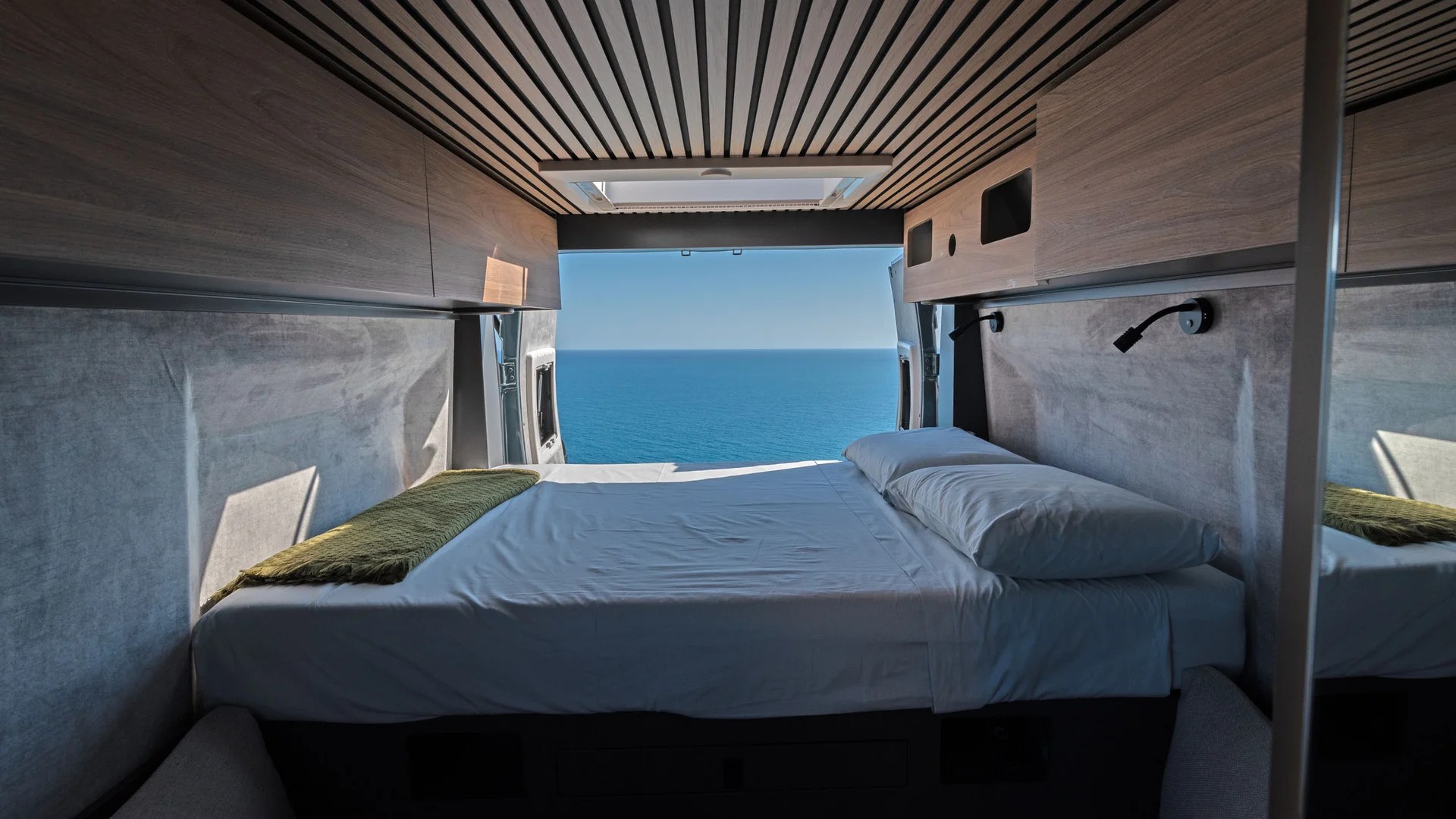 Innenraum eines Vans mit Bett und Meerblick