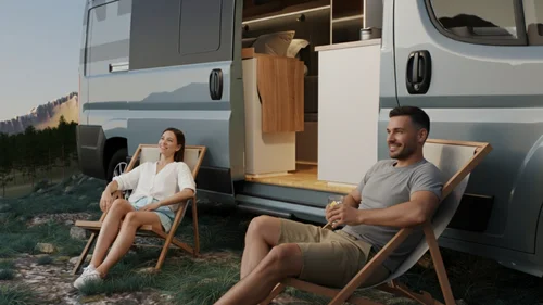 Coppia seduta su sedie a sdraio vicino a un camper in un paesaggio naturale