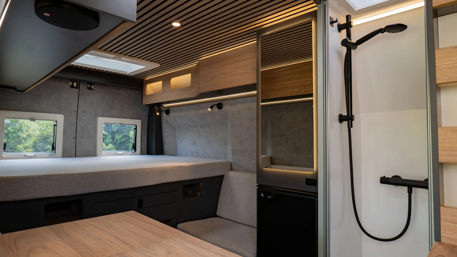 Interno moderno di camper con letto, tavolo e doccia