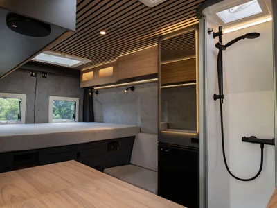 Interno moderno di camper con letto, tavolo e doccia
