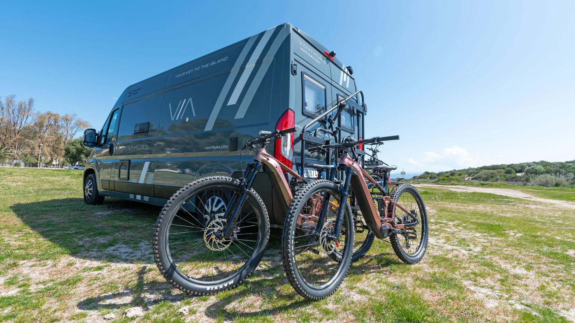 Schwarzer Camper mit zwei Elektrofahrrädern hinten geparkt
